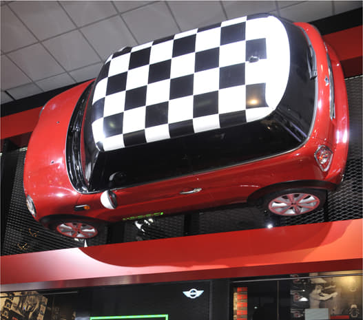 The checkered flag top Mini suspended on a wall at the Mini stall