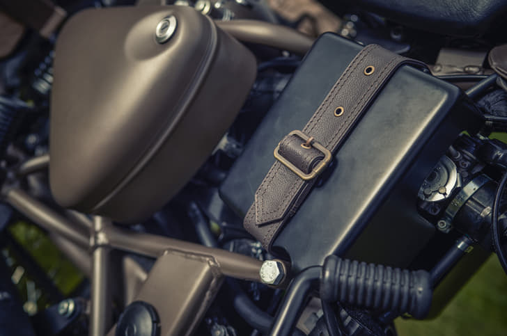 Leather strap with brass buckles on the air box.