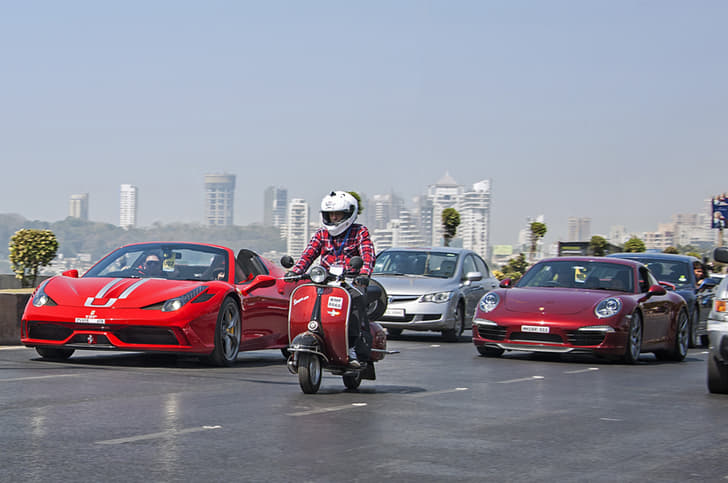 Yohan Poonawalla’s Ferrari 458 Speciale Aperta seen alongside a vintage Vespa and a Porsche 911.