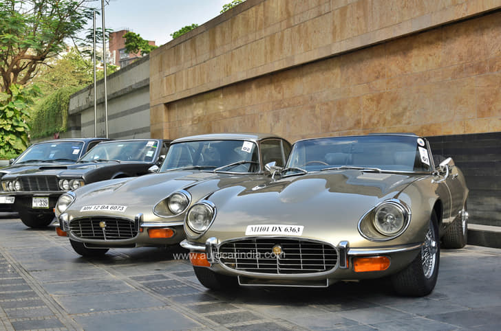 Two pristine examples of Jaguar E-Types – a coupe and a convertible. Both powered by V12s. An Aston Martin DBS lurking in the background. 
